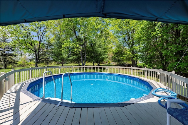 view of swimming pool with a deck and view of wooded area