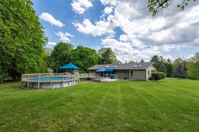 back of property with a yard, an outdoor pool, a deck, and a patio area