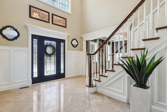 33 Bacon Rd, Saint James, NY 11780 - entryway featuring a decorative wall, a high ceiling, marble tiled flooring, wainscoting, and stairs
