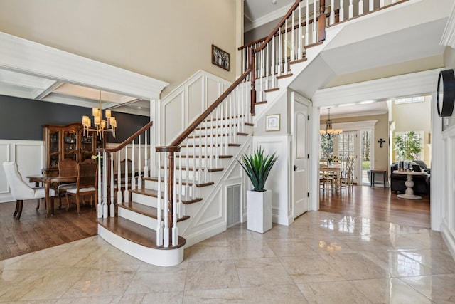 33 Bacon Rd, Saint James, NY 11780 - stairway featuring a chandelier, a decorative wall, marble tiled flooring, ornamental molding, and a towering ceiling