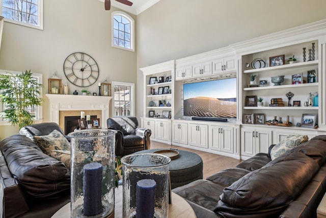 33 Bacon Rd, Saint James, NY 11780 - living area with ceiling fan, a glass covered fireplace, a towering ceiling, wood finished floors, and crown molding