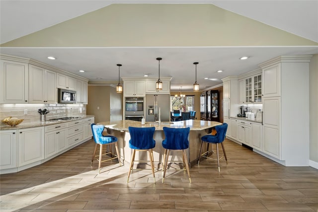 3 Bell Ct, Airmont, NY 10901 - kitchen featuring wood finish floors, vaulted ceiling, a breakfast bar, stainless steel appliances, and a center island with sink