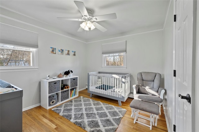 3 Bell Ct, Airmont, NY 10901 - bedroom featuring a baseboard heating unit, baseboards, a nursery area, ceiling fan, and wood finished floors