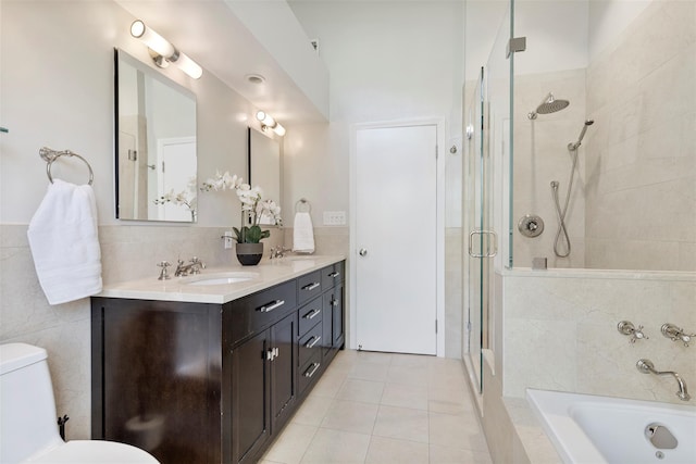bathroom featuring tiled tub, a tile shower, a sink, tile patterned floors, and toilet