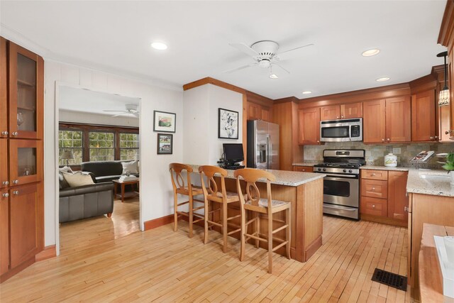 29 Oscaleta Rd, South Salem, NY 10590 - kitchen with light wood finished floors, stainless steel appliances, a ceiling fan, decorative backsplash, and a kitchen bar