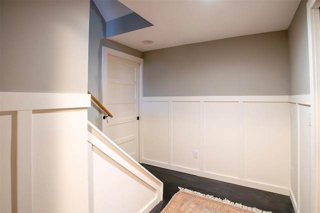 stairs featuring wainscoting, wood finished floors, and a decorative wall