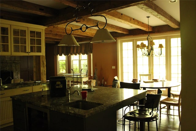 7 Locust Ln, Glen Head, NY 11545 - kitchen with a sink, beamed ceiling, dark stone countertops, an island with sink, and a kitchen breakfast bar