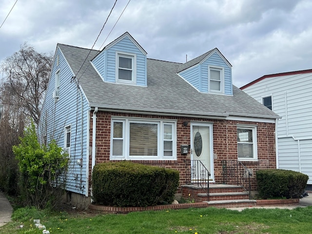 new england style home with a shingled roof and brick siding