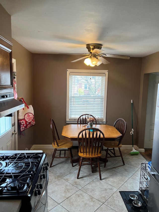 dining space with a ceiling fan, baseboards, and light tile patterned flooring
