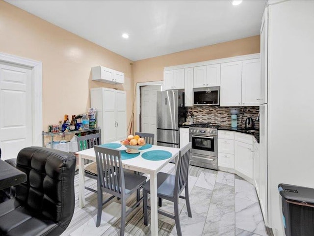 kitchen with white cabinets, appliances with stainless steel finishes, decorative backsplash, and marble finish floor