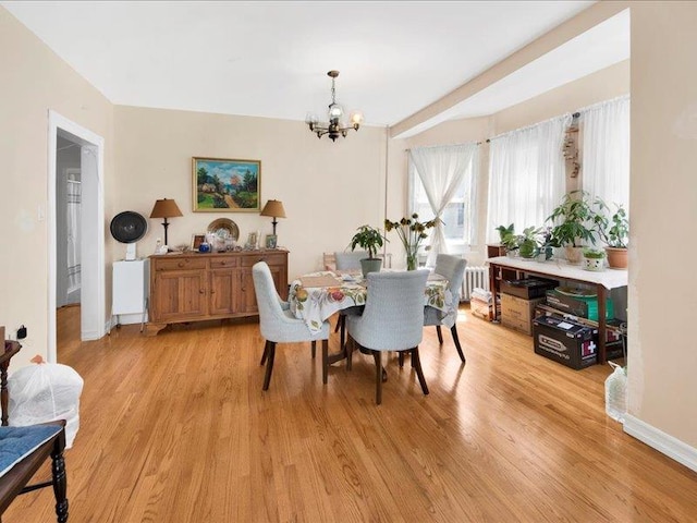 dining room with baseboards, an inviting chandelier, radiator heating unit, and light wood-style floors