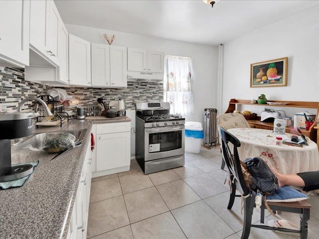 kitchen with stainless steel gas range, white cabinetry, under cabinet range hood, and decorative backsplash