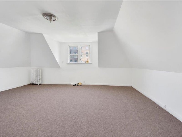 additional living space with vaulted ceiling, carpet, baseboards, and radiator