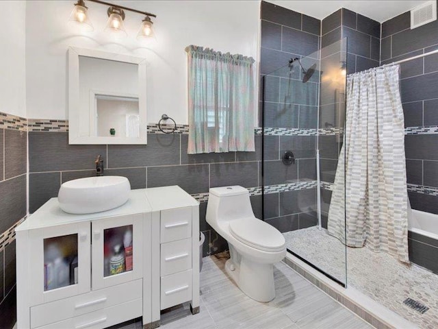full bath with toilet, tile walls, tiled shower, and vanity