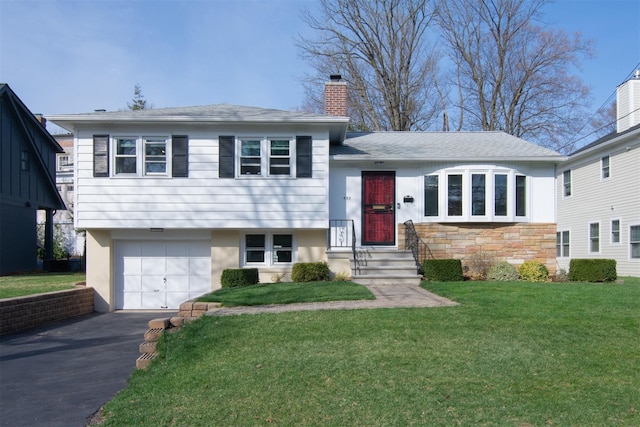435 Carol Pl, Pelham, NY 10803 - tri-level home featuring stone siding, a garage, a chimney, a front lawn, and driveway