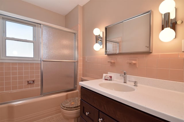 435 Carol Pl, Pelham, NY 10803 - bathroom with tile walls, vanity, a wainscoted wall, toilet, and bath / shower combo with glass door