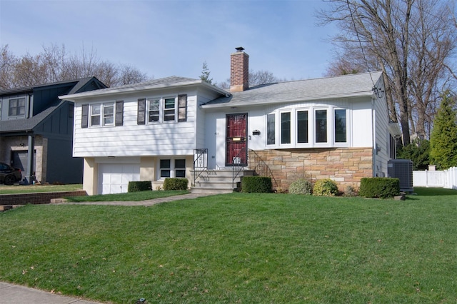 435 Carol Pl, Pelham, NY 10803 - tri-level home with stone siding, a garage, a chimney, cooling unit, and a front lawn