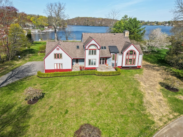 view of front of home with a water view, a chimney, a shingled roof, and a front yard