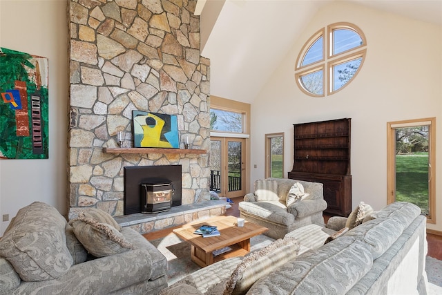 living room featuring french doors, a wood stove, wood finished floors, and high vaulted ceiling