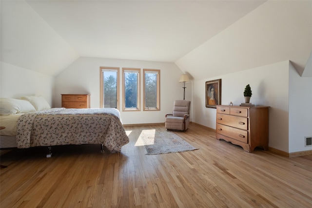 bedroom with visible vents, baseboards, light wood finished floors, and lofted ceiling