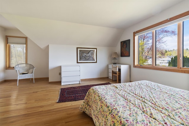 bedroom featuring baseboards, light wood-style flooring, and lofted ceiling