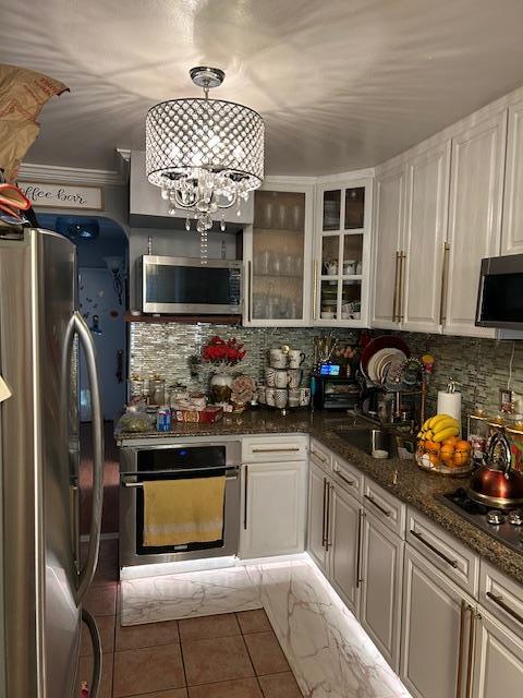 1248 E 84th St, Brooklyn, NY 11236 - kitchen with stainless steel appliances, tile patterned flooring, tasteful backsplash, and glass insert cabinets
