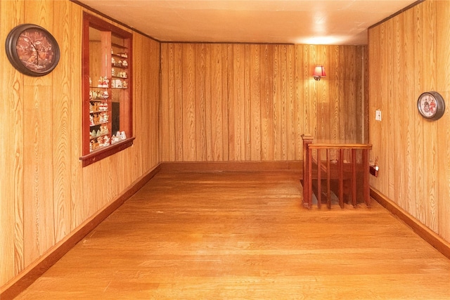 corridor featuring baseboards, built in shelves, wood finished floors, and wood walls
