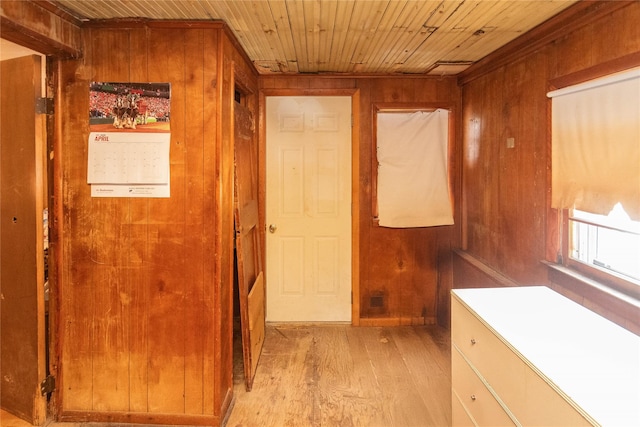 corridor featuring light wood-style flooring, wooden ceiling, and wood walls