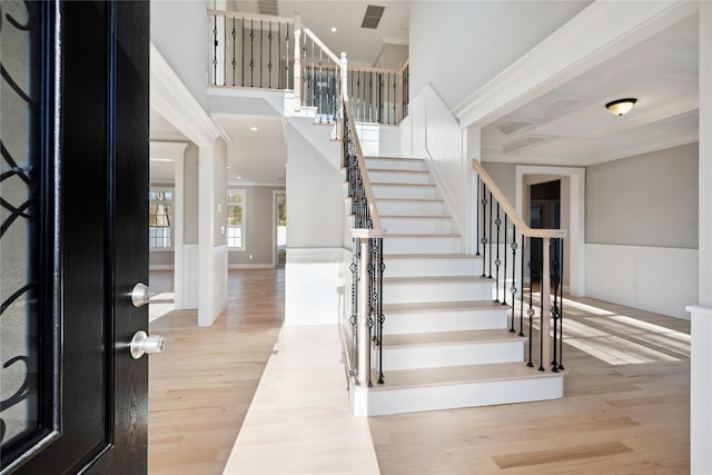 foyer with stairway, wood finished floors, a towering ceiling, and ornamental molding