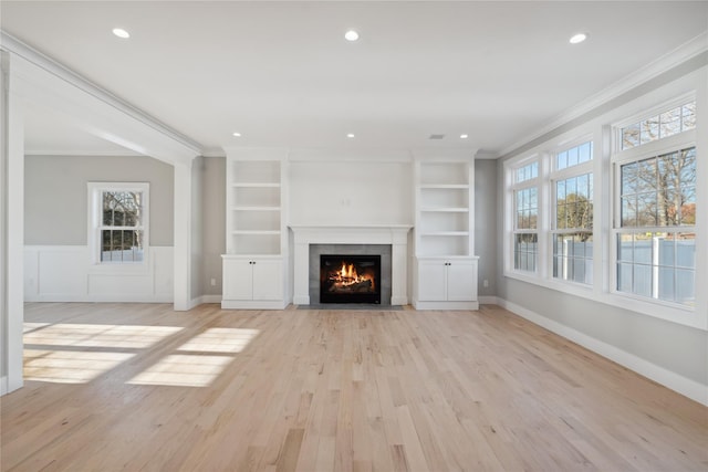 unfurnished living room featuring recessed lighting, ornamental molding, a fireplace with flush hearth, and light wood-style flooring