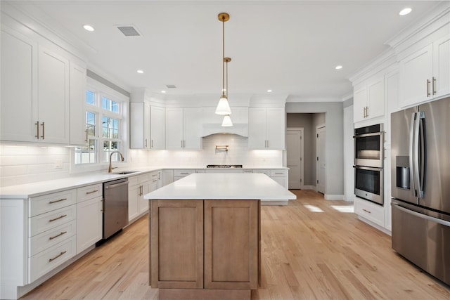 kitchen featuring decorative backsplash, a sink, stainless steel appliances, light countertops, and ornamental molding