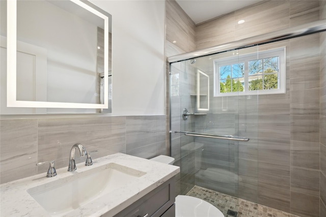 full bathroom with tile walls, a shower stall, toilet, and vanity