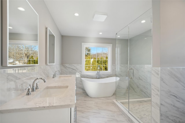 full bath with a stall shower, tile walls, a sink, and a freestanding tub