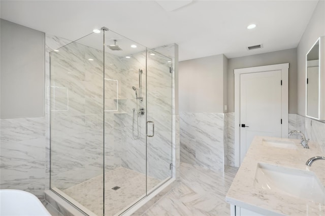 bathroom featuring tile walls, visible vents, a marble finish shower, and a sink