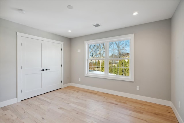 unfurnished bedroom with recessed lighting, a closet, light wood-type flooring, visible vents, and baseboards