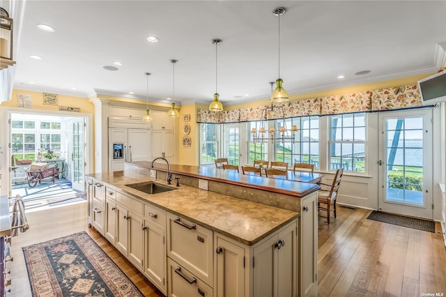 279 Little Neck Rd, Centerport, NY 11721 - kitchen featuring a sink, pendant lighting, a center island with sink, light wood-style floors, and ornamental molding