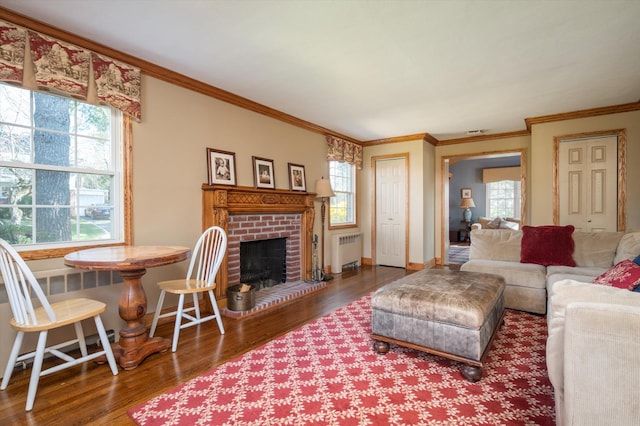 56 Milburn Ln, East Hills, NY 11577 - living area featuring radiator, wood finished floors, ornamental molding, a brick fireplace, and baseboards