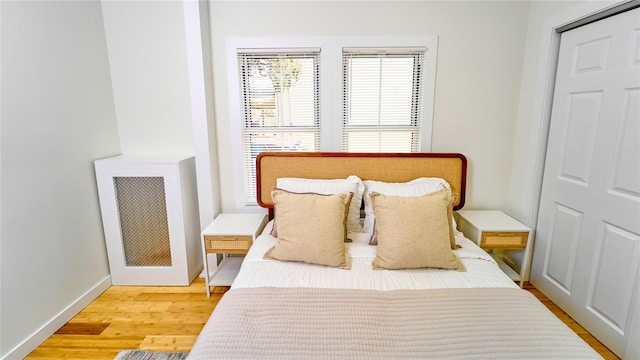 bedroom featuring baseboards, wood finished floors, and radiator heating unit