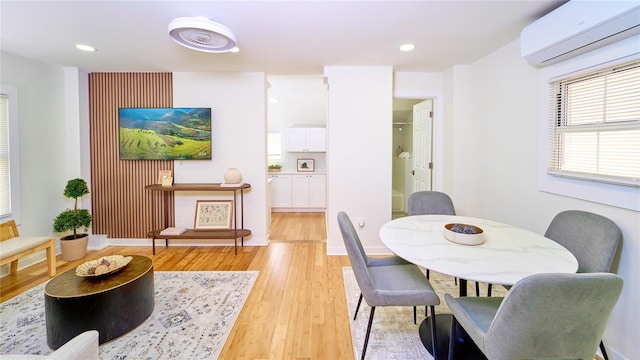 dining space with an AC wall unit, recessed lighting, and light wood-style floors