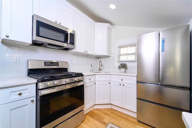 kitchen with light countertops, appliances with stainless steel finishes, a sink, and white cabinetry