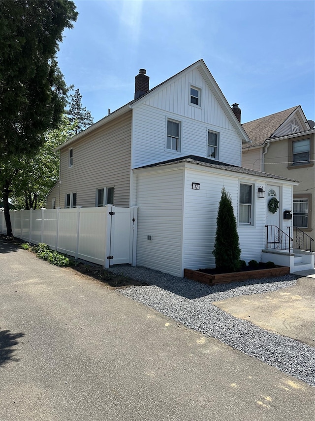 view of home's exterior with fence, a gate, board and batten siding, and a chimney