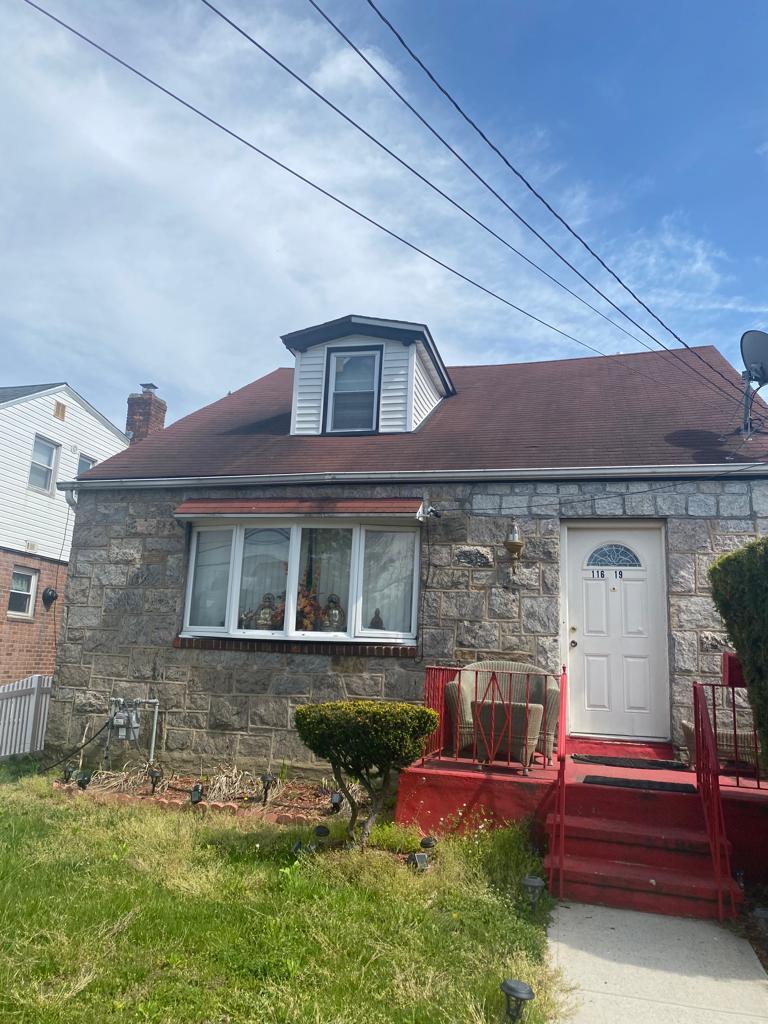 116-19 240th St, Elmont, NY 11003 - view of front facade featuring stone siding, a front yard, fence, and a chimney
