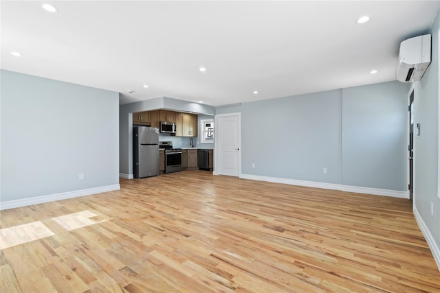 unfurnished living room with light wood finished floors, baseboards, a wall mounted AC, and recessed lighting