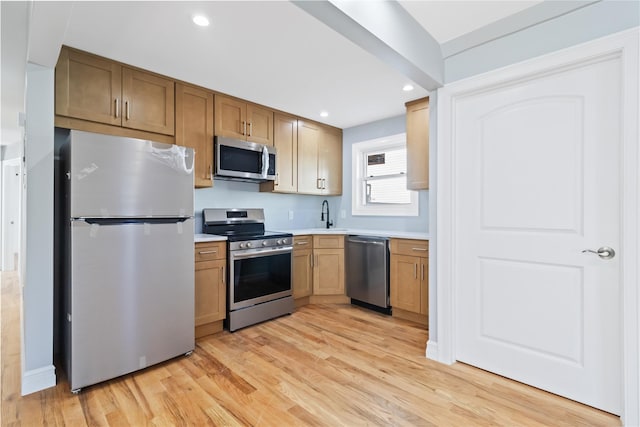 kitchen featuring light countertops, a sink, stainless steel appliances, light wood-style floors, and recessed lighting