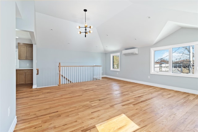 spare room with an inviting chandelier, an AC wall unit, vaulted ceiling, and light wood-type flooring