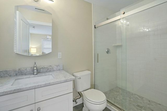 full bathroom featuring a shower stall, toilet, and vanity