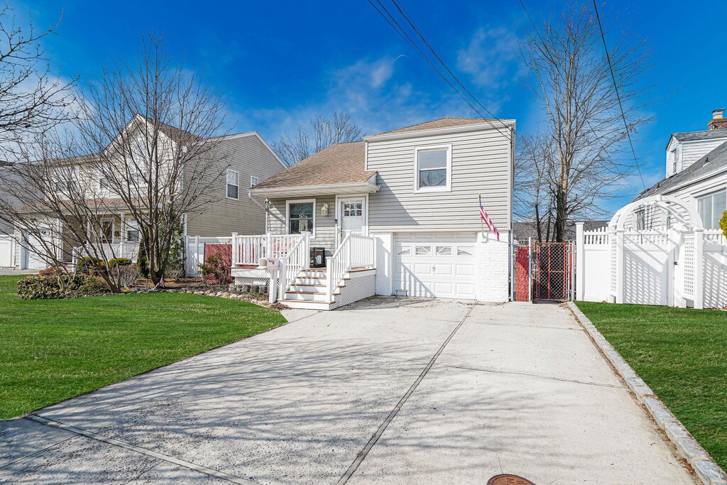 43 Coolidge Ave, Amity Harbor, NY 11701 - split level home featuring a gate, fence, a garage, concrete driveway, and a front yard