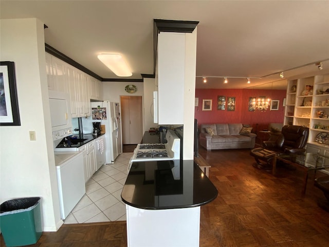 kitchen with stacked washer and clothes dryer, white cabinetry, ornamental molding, and white appliances