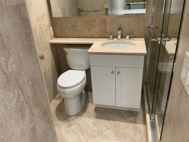 bathroom featuring tile walls, toilet, a stall shower, and vanity