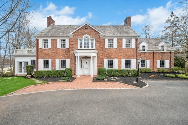 85 Station Rd, Great Neck, NY 11023 - view of front of house with a chimney, a front lawn, french doors, and brick siding